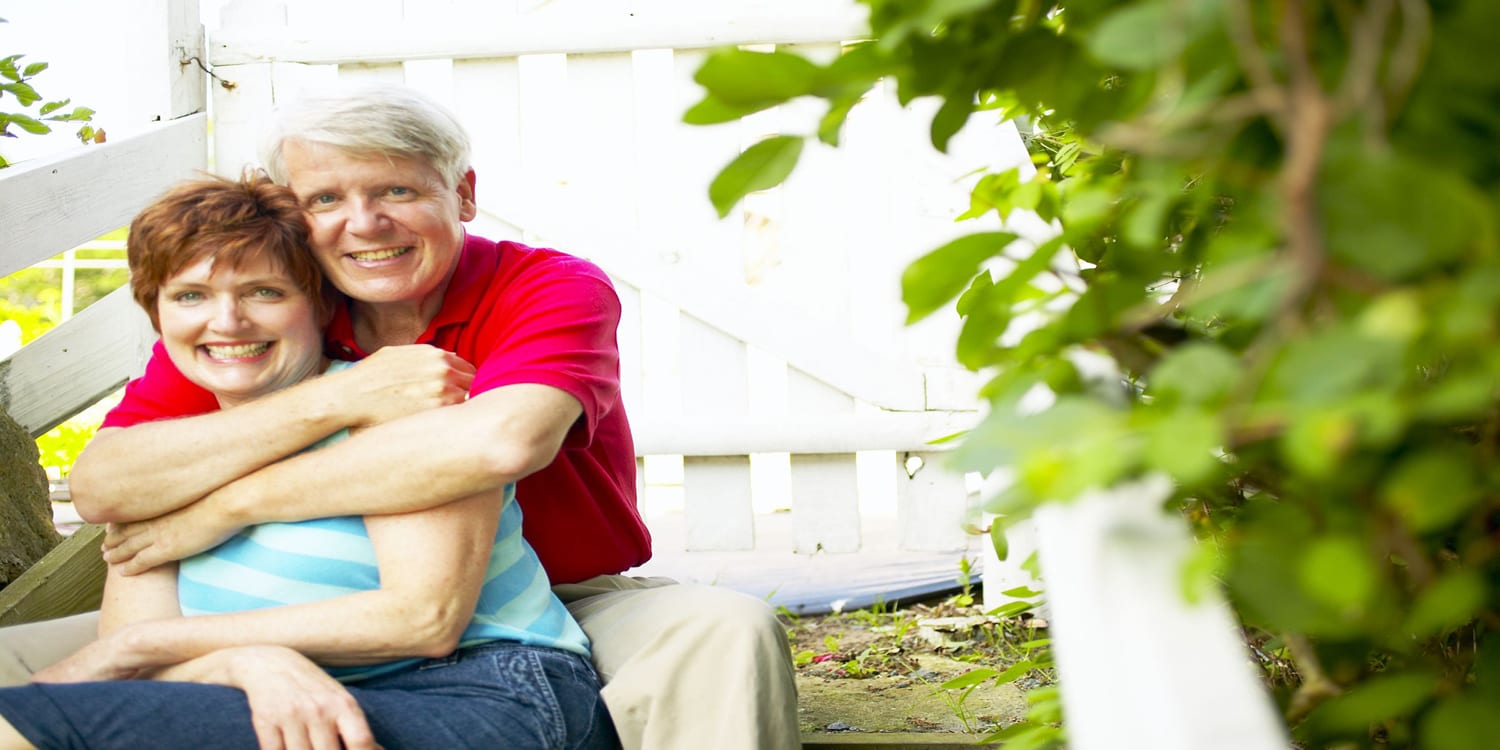 Happy older couple in front of house